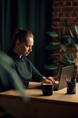 Overworking,. Serious, concentrated, intelligent business woman sitting at table and working on laptop in her office. Concept of business, fashion, career development, profession, occupation