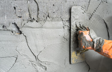 Hand worker plastering cement wall background, grey concrete stucco well free space for text presentation 