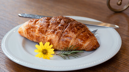 Fresh envelopes are placed on the white plate, knives and forks and yellow flowers are placed on the wooden table.