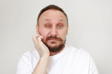 Obraz premium shot mans hand is unrestrained scratching unshaven chin. Overgrown unkempt male in white t shirt with thick beard and mustache face. Beauty salon concept, barbershop