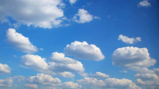White cumulus clouds float slowly in the blue sky. A dreamy background with clouds smoothly changing their shape.