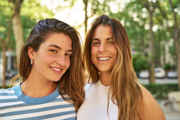 Two friends smiling happily in a park.