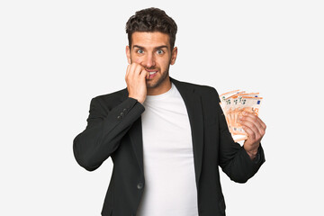 Young business caucasian man holding euro banknotes biting fingernails, nervous and very anxious.