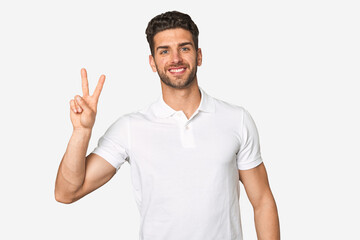 Fototapeta premium Young handsome man isolated joyful and carefree showing a peace symbol with fingers.