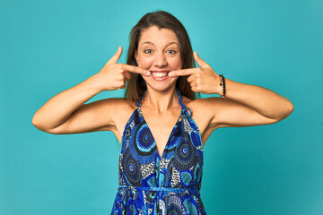 A young caucasian woman isolated smiles, pointing fingers at mouth.