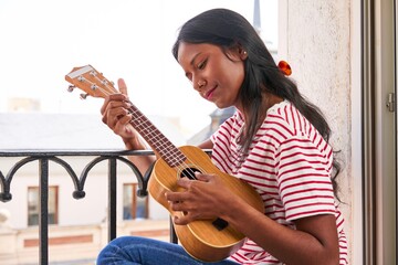 Indian woman playing ukulele on windowsill