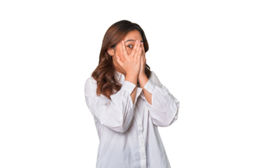 A young chinese woman blink through fingers frightened and nervous.