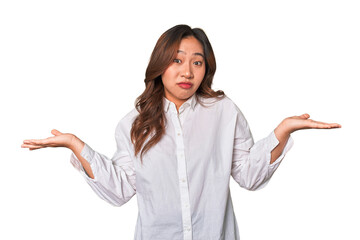 A young chinese woman doubting and shrugging shoulders in questioning gesture.