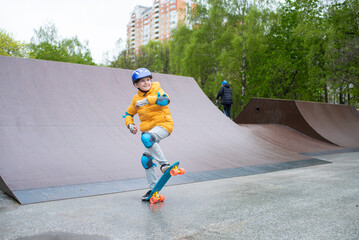 a child rides a blue city cruiser, a plastic bright skateboard, in a skate park on a halfpipe