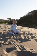 Fototapeta na wymiar A baby girl sitting on a dune at the beach during a family vacation