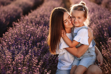 Happy family in purple lavender field. young beautiful mother and child Girl enjoy walking blooming...
