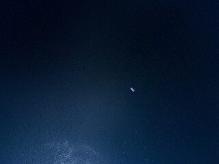 Aerial top down view of an unidentified man on the inflatable mattress relax and enjoys sun on deep...