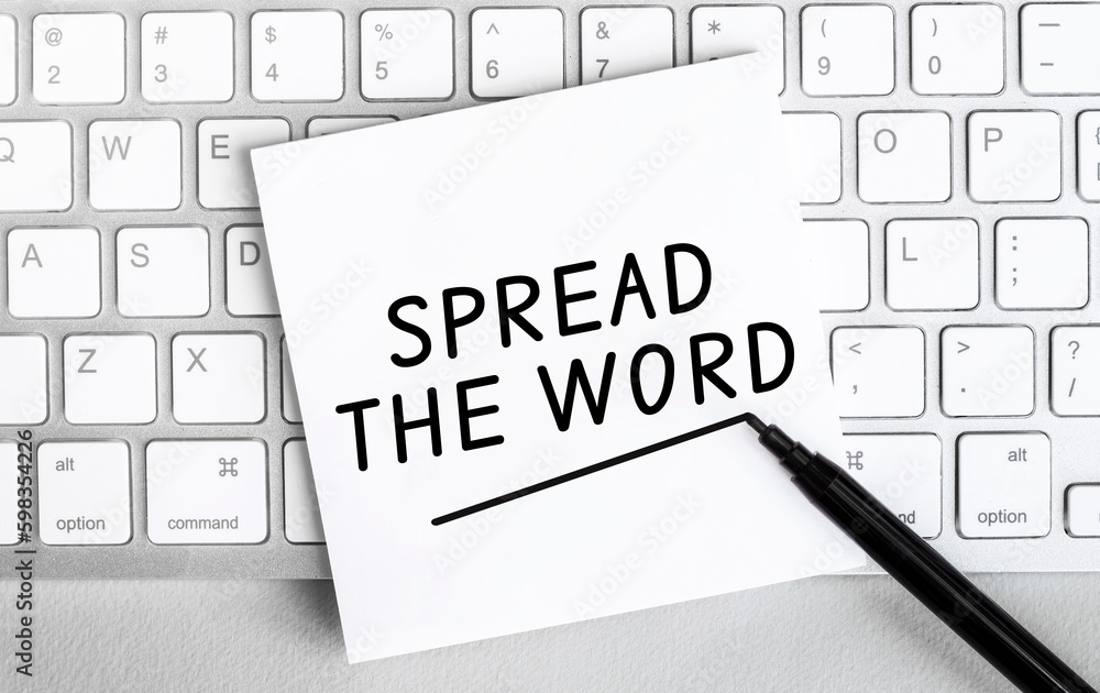Poster white paper with text spread the word lying on the keyboard