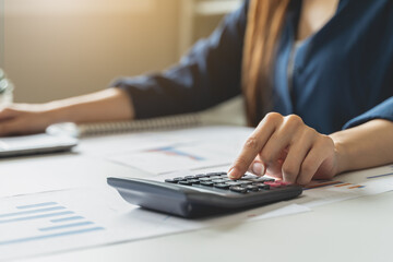 Women business people use calculators to calculate the company budget and income reports on the desk in the office.