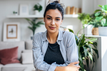 Confident woman having videocall with laptop while looking at camera sitting in living room at home.