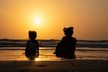kids enjoying sunset view from the beach, two kids sitting on the beach during sunset