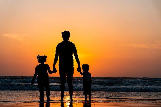 Father with kids on the beach at sunset, Father's day concept image, beautiful family photo