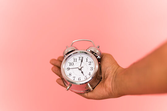 Holding alarm clock with copy space, time concept image