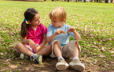 Little childrens sit on a grass in the park