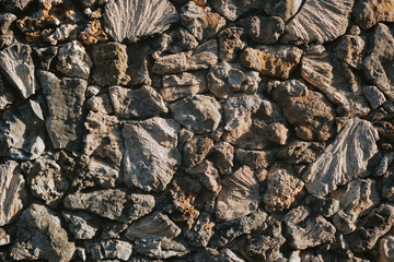 Textured gray wall made of natural stone close-up.