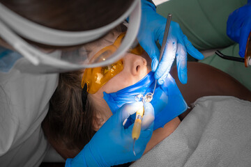 Applying resin based composite filling on tooth. Young woman at dental clinic. Female dentist with...