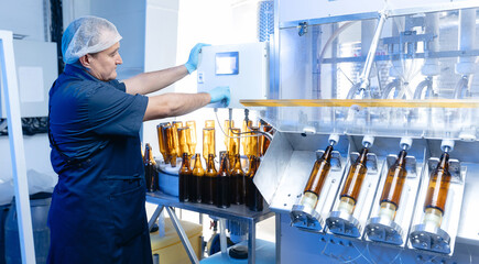 Male operator engineer controls production line brewery from control panel, food beer factory