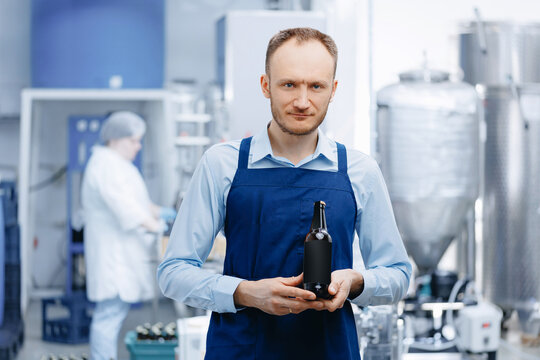 Man worker hold bottle with craft beer on Brewery Industry production, control quality background conveyor for drink
