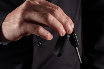 Businessman holding a car key on dark background