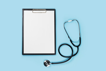 Blank medical clipboard with stethoscope on blue background concept. Copy space.