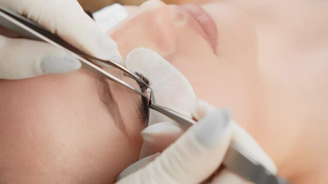 Master lashmaker neatly applies each cilia to natural eyelashes, giving volume and length. Woman builds eyelashes in beauty clinic with professional cosmetologist. Combination care and Generative AI