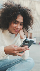 Close up, young woman scrolls on a cell phone. Happy girl uses mobile phone on old city background