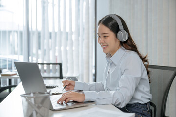 Smiling customer support service operator help desk. Young operator asian woman agent with headsets working support hotline in a call centre.