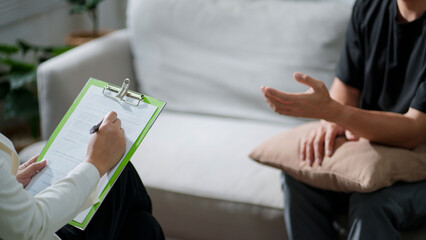 PTSD, Sad man with psychologist taking notes during therapy session..