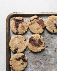 Homemade chocolate stuffed cookies on a parchment lined baking sheet, vanilla and chocolate cookies, thick vanilla cookies with a chocolate filling	
