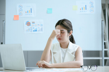 Exhausted young businesswoman are stressed and tired having headaches at office desk. Asian woman...