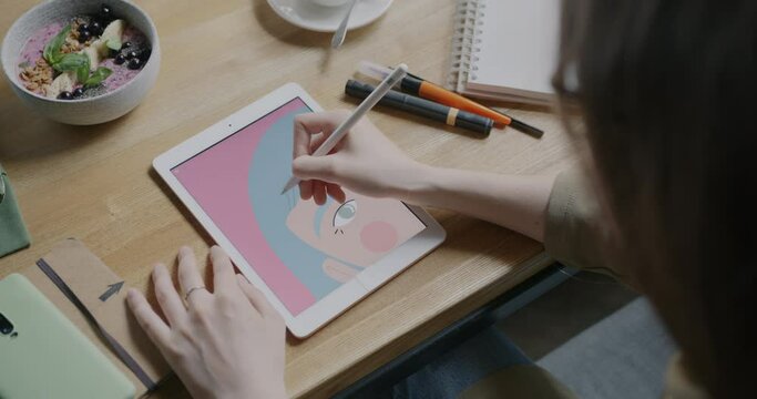 Close-up of female hand creating portrait with graphics tablet drawing with stylus at table in cafe. Modern device and freelance work concept. Generative AI