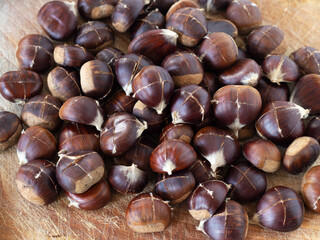 Closeup of brown chestnuts with cut on top of a wooden table. Top view. Healthy organic autumn food.