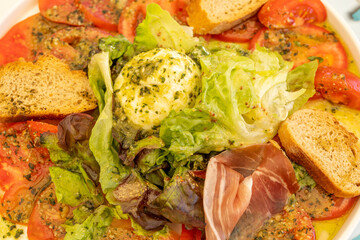 Whole buffalo mozzarella with pesto sauce, salad leaves, tomatoes and spanish sausage