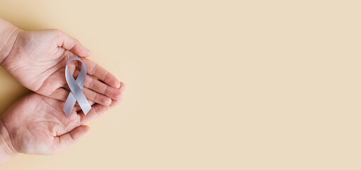 World Brain Tumor day. Person's hands are holding a gray ribbon. This is observed every year on June 8th.