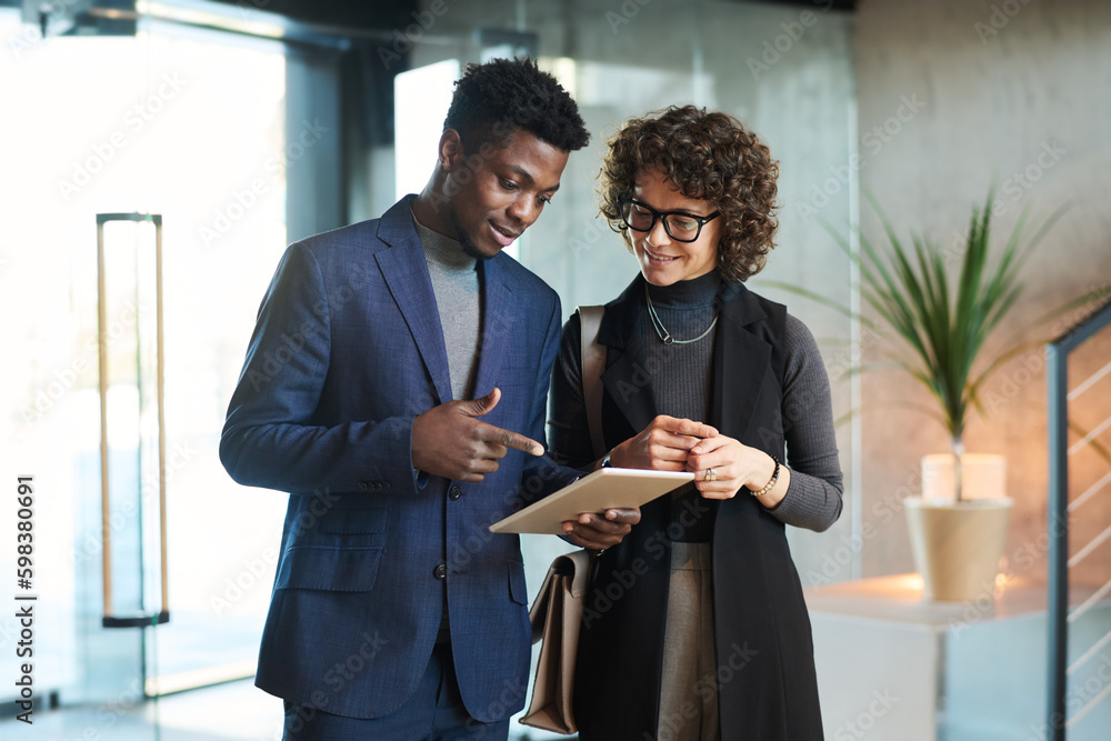 Aufkleber Young confident African American manager pointing at tablet screen while making presentation of new project points to female colleague