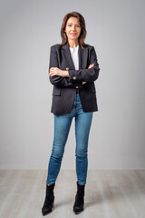 Full length of an attactive woman wearing blazer and jeans and standing at isolated bacgkround