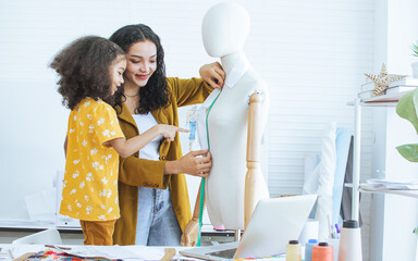 Professional hipster female tailor and daughter measuring mannequin in shop, room, home studio, making, designing fashion dress or clothes. Small Business and Lifestyle Concept.