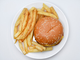 Meat burger with French fries on a white plate. Delicious fast food breakfast. Hamburger.