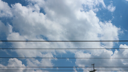 Fototapeta premium Electric wires and electric poles crossing the high voltage pole tower against the blue sky background.