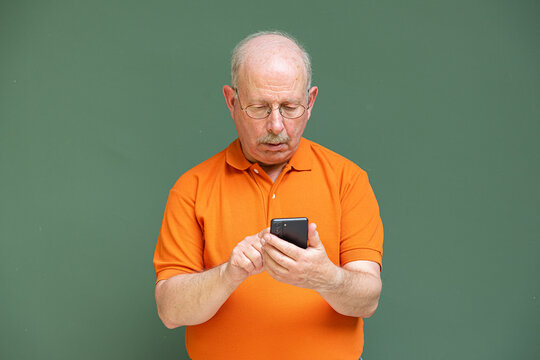 Grey haired senior man with mustache wearing eyeglasses and using mobile phone
