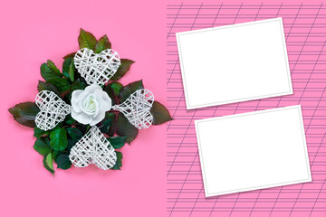 Fototapeta na wymiar Beautiful white roses with green foliage and heart for Valentine's Day on pink paper background. Creative greeting card.