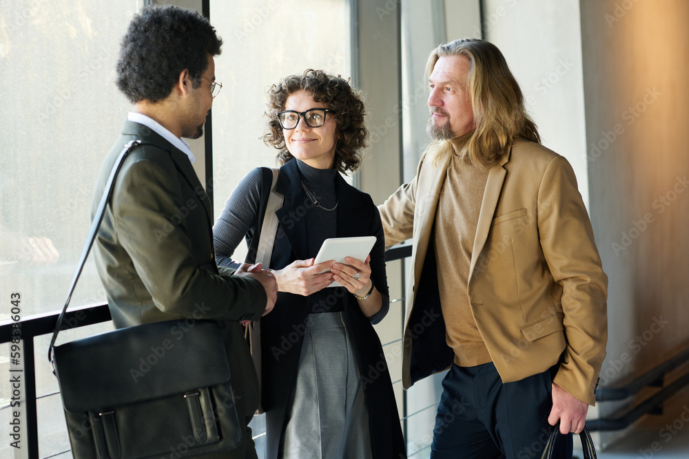 Poster Group of three intercultural white collar workers in smart casualwear brainstorming while discussing project points or organizing work
