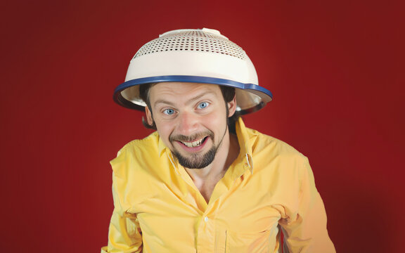 A grinning ugly crazy man wearing a colander (madness, insanity, conspiracies). Generative AI.
