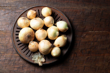 pile of onions on rustic wood, top view, space for text
