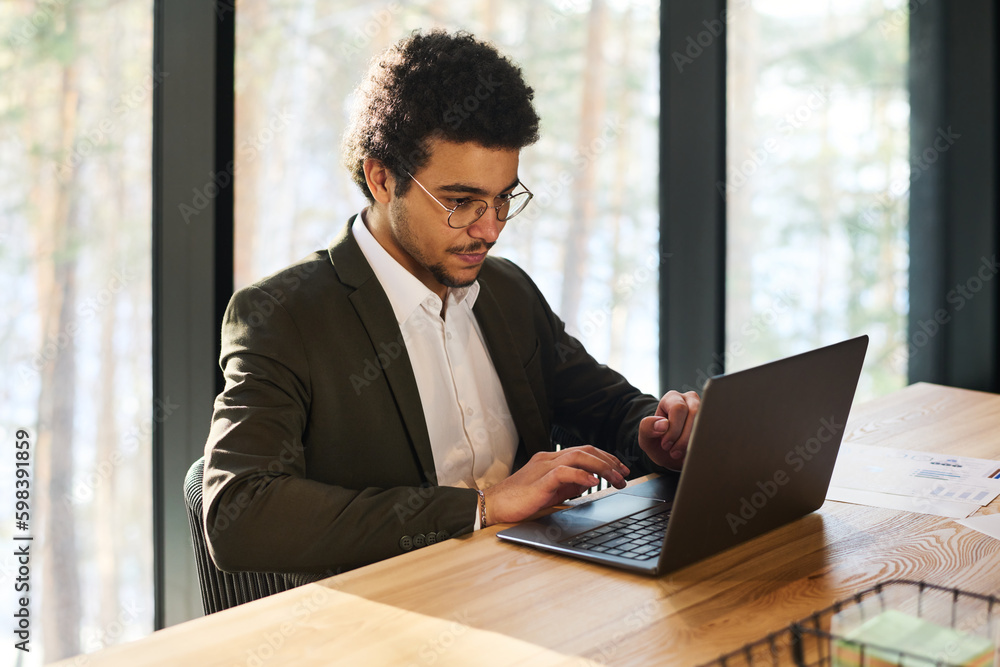 Aufkleber serious young analyst or broker looking at laptop screen by workplace while analyzing online financi